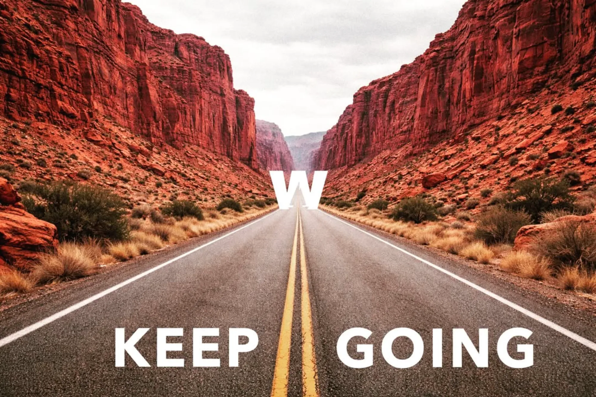 A desert canyon road stretching to the horizon with the Weathered Sailor W and the words KEEP GOING