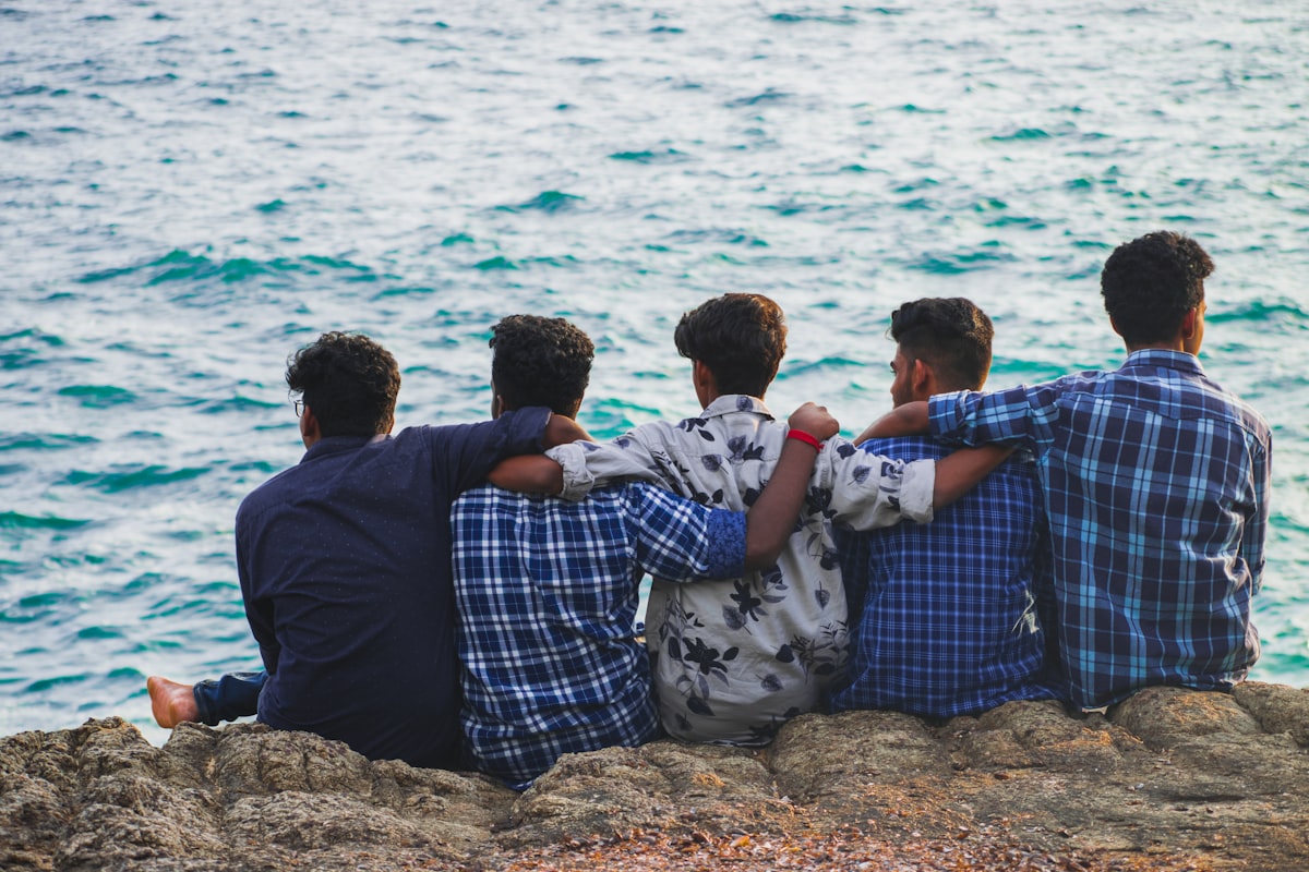 five men on rocks by water