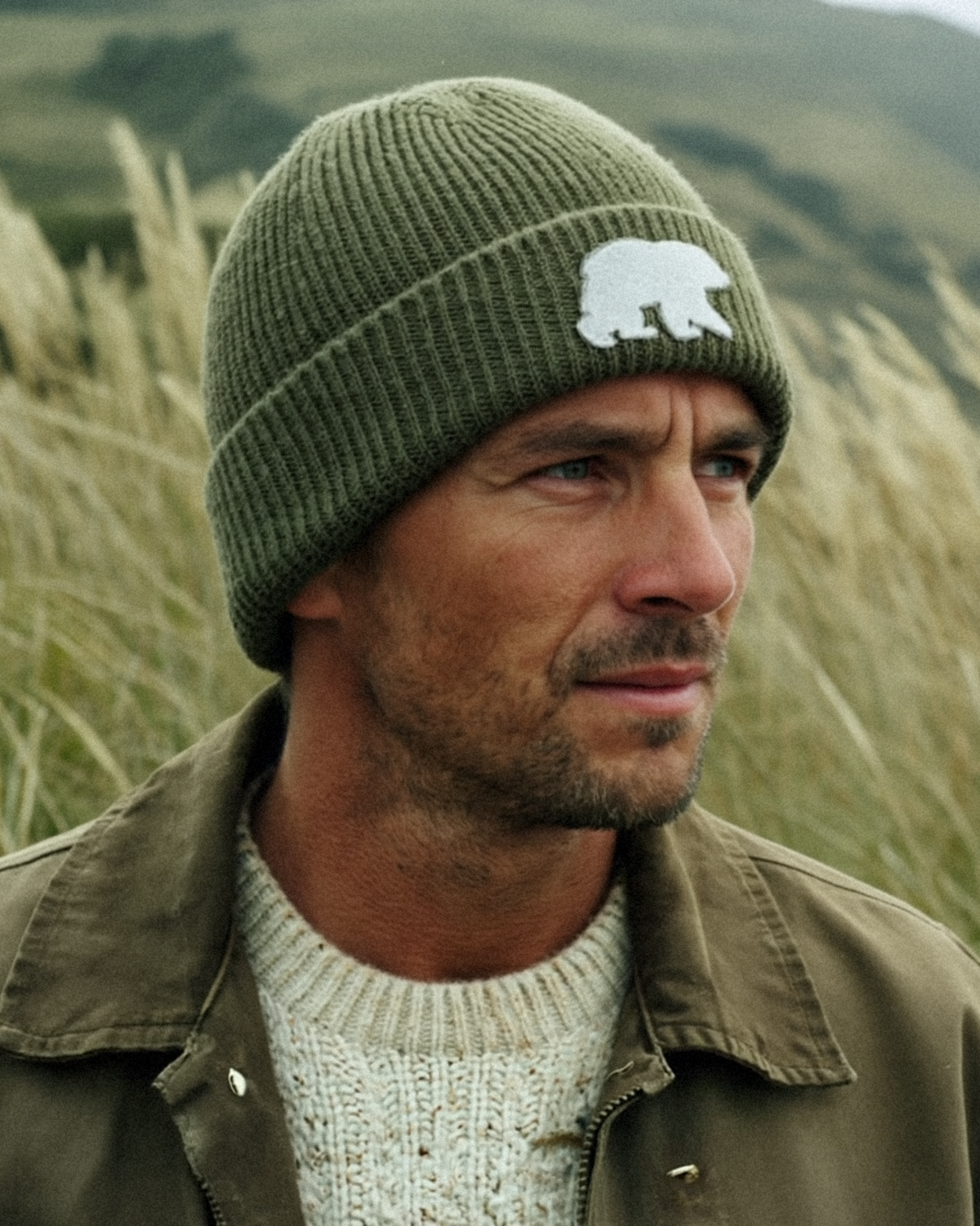 Person wearing the olive Bear beanie outdoors, showing the folded cuff and white Bear patch.