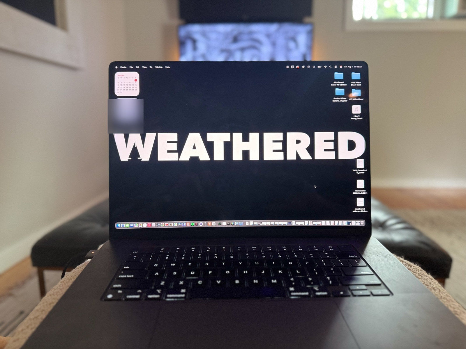 A laptop open on a bench in the evening, the Weathered Sailor wordmark filling the screen.