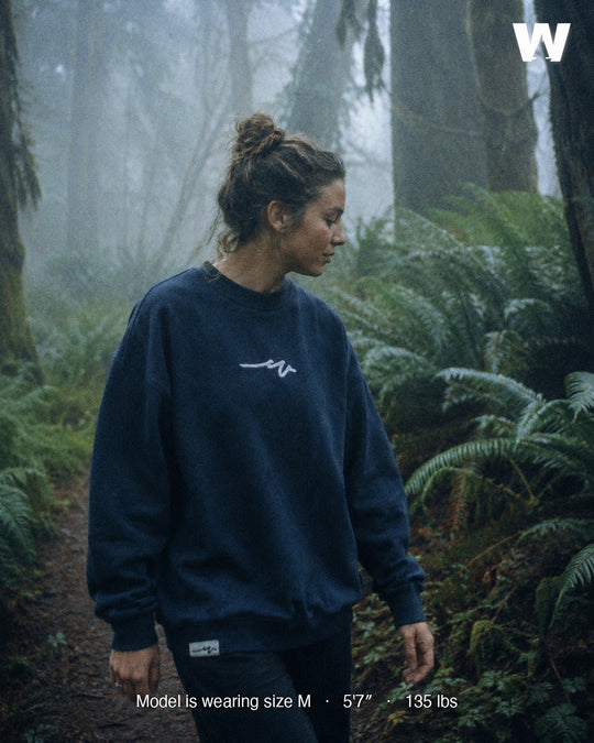 Model wearing the Ink Blue Puff Dub Heavy Terry Crew on a misty old-growth forest trail — size M