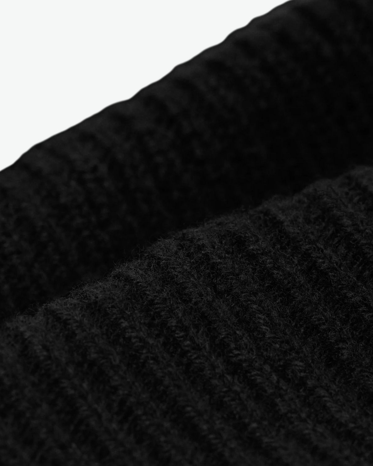 Close-up of the black beanie's ribbed knit and folded cuff.