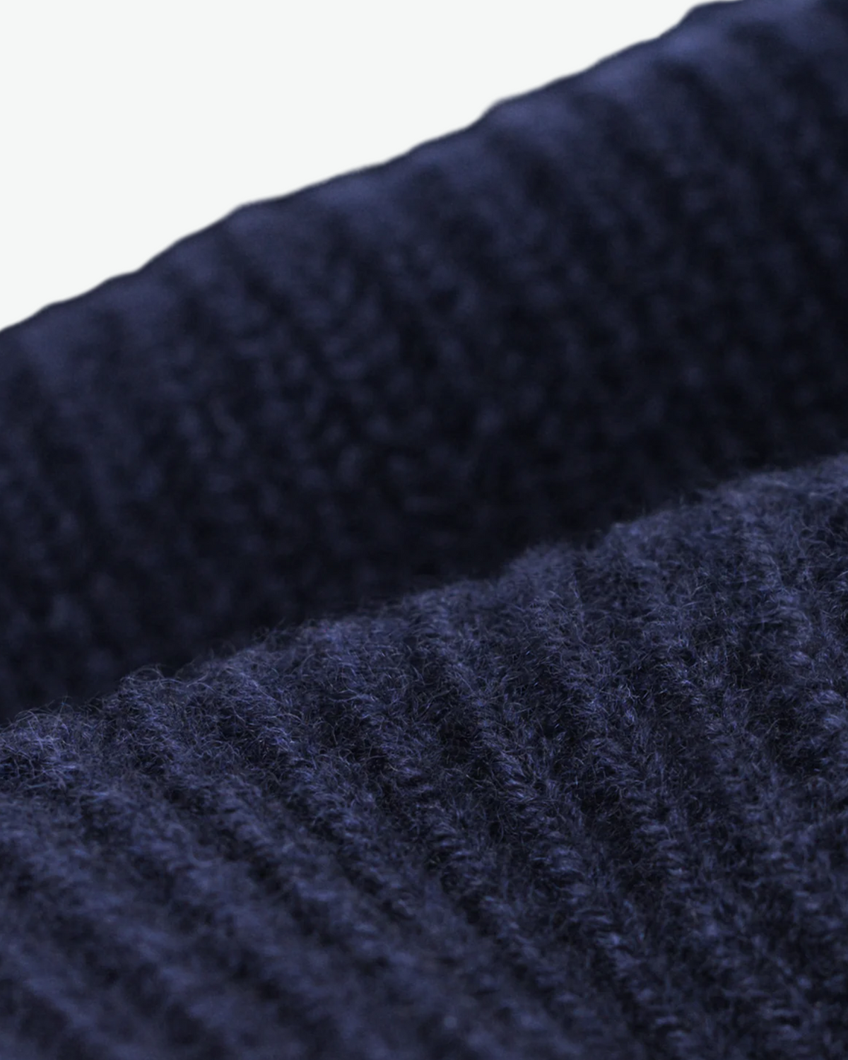 Close-up of the navy beanie's ribbed knit and folded cuff.