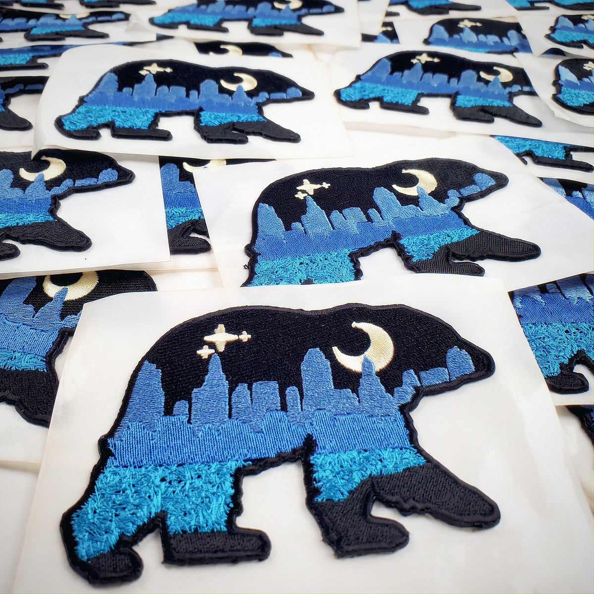 A production run of embroidered Bear patches laid out together.