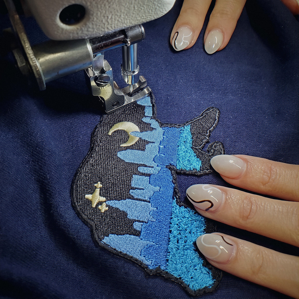 A Bear patch being sewn onto a garment on a sewing machine.